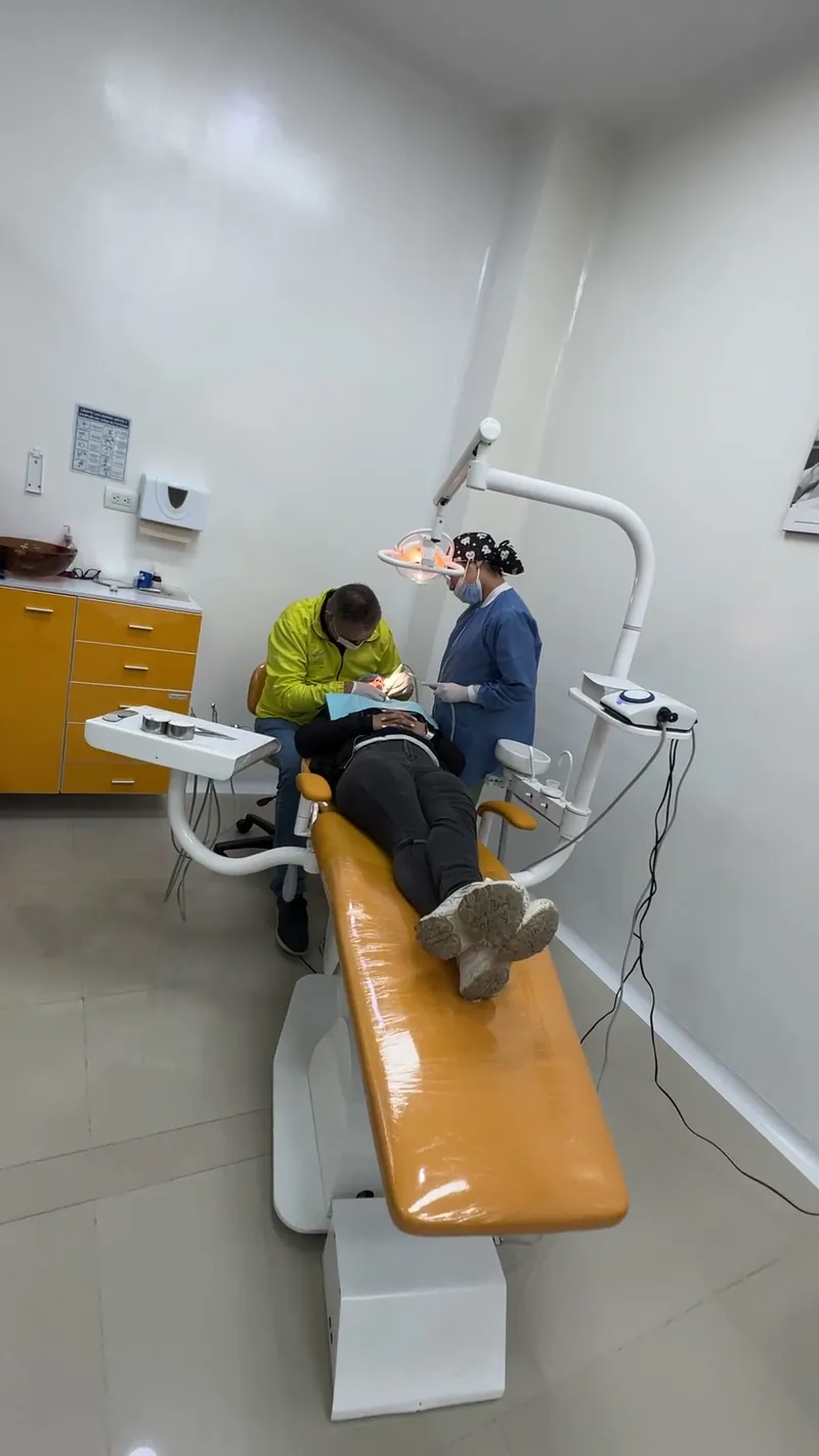 Sala de atención con el sillón amarillo y el odontólogo atendiendo a un paciente