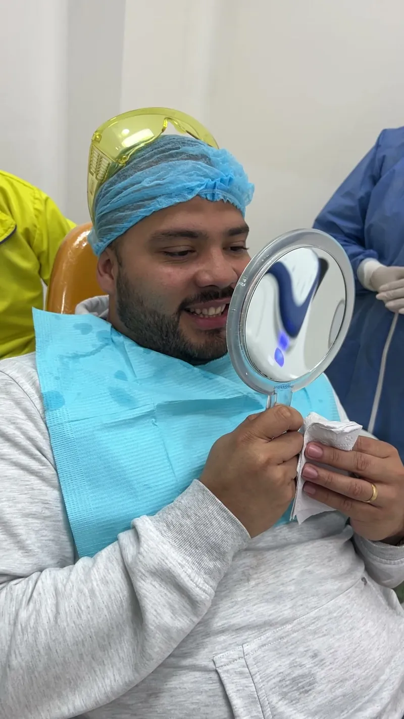 Un paciente se mira la sonrisa en un espejo al terminar la cita